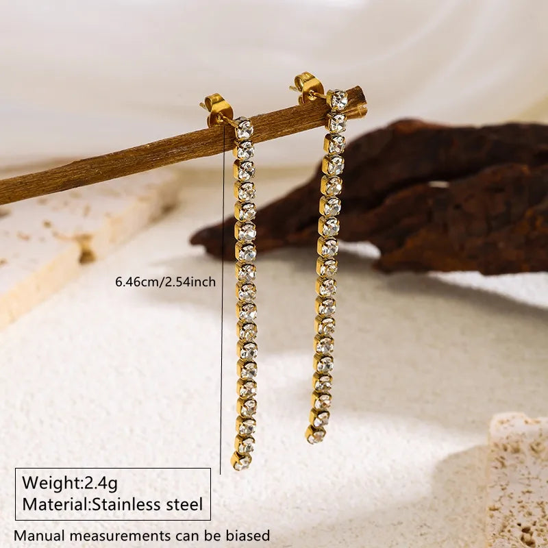 Aramat Jewels lange goudkleurige RVS oorhangers met rij van transparante kristallen en vlindersluiting
