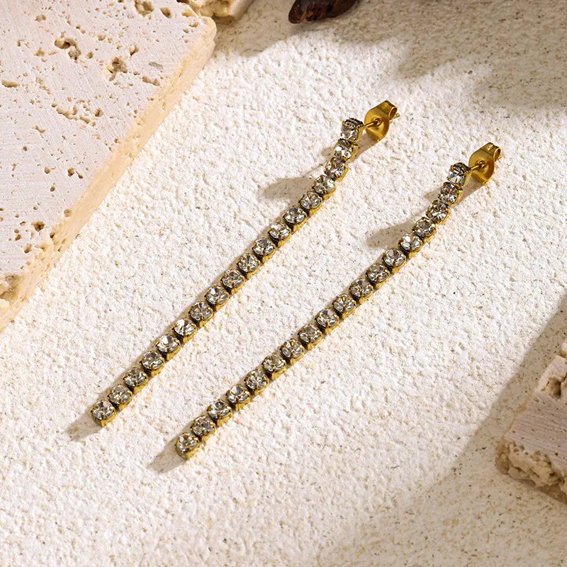 Aramat Jewels lange goudkleurige RVS oorhangers met transparante kristallen in een slank, elegant ontwerp.