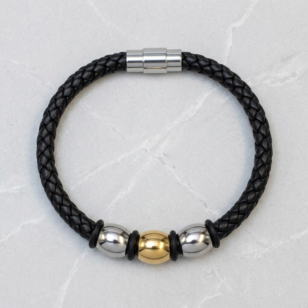 Aramat Jewels gevlochten zwarte leren herenarmband met zilver- en goudkleurige stalen kralen en magneetsluiting.