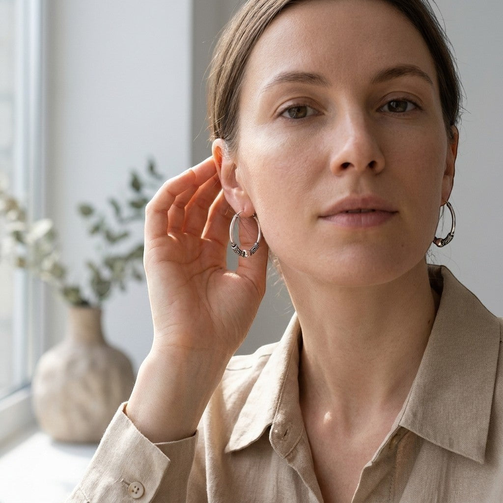 Aramat Jewels 18mm oxidized silver Bali hoop earrings with ethnic patterns, worn by a woman.