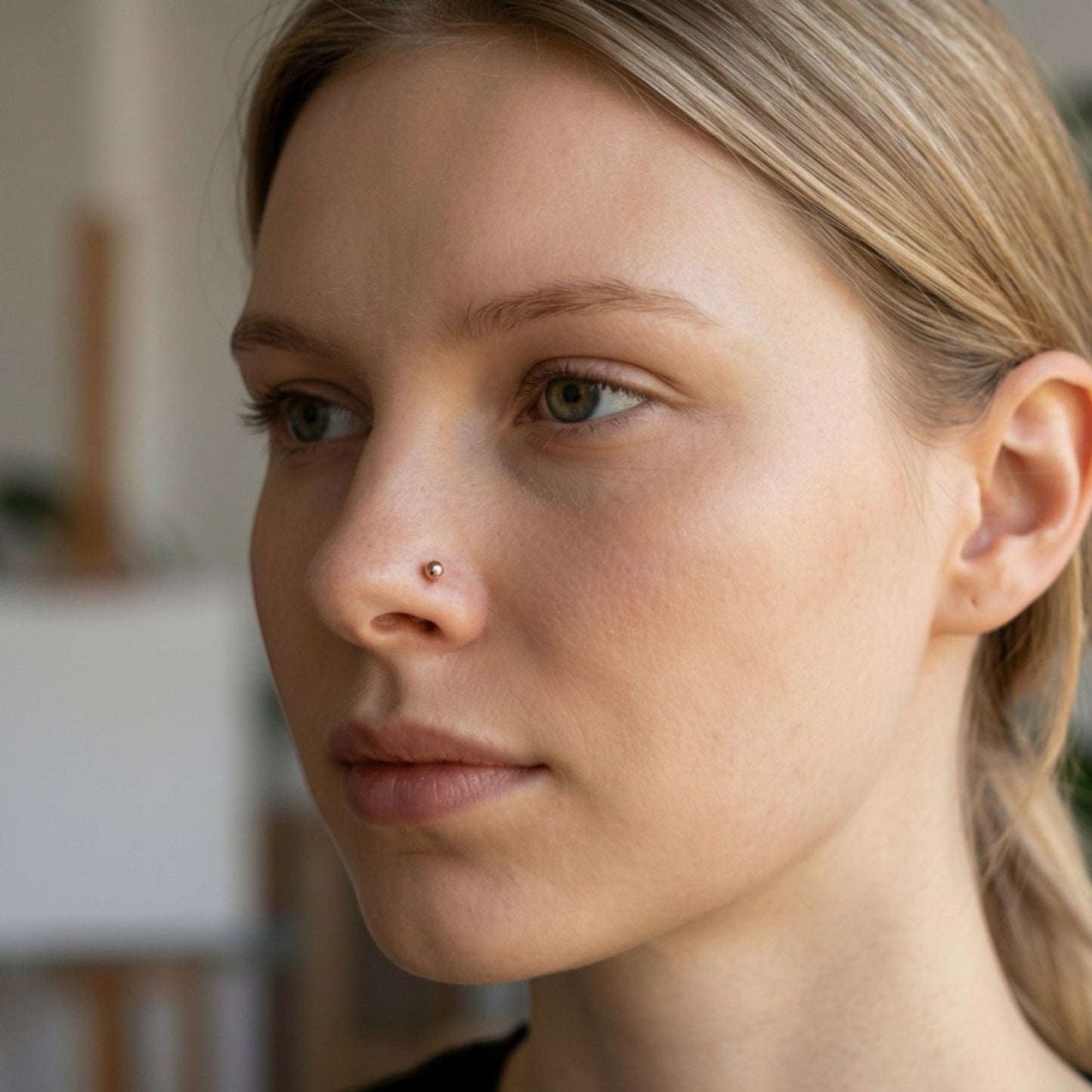 Aramat Jewels rosegoudkleurige stalen neuspiercing met 2mm bolletje gedragen door een vrouw voor een elegante look.