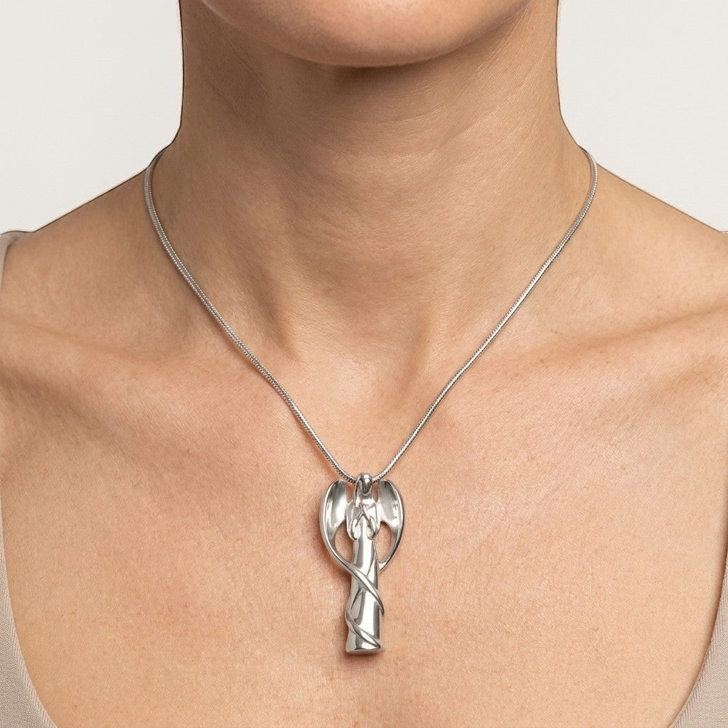Aramat Jewels silver-colored stainless steel angel ash pendant on a snake chain necklace worn by a woman.