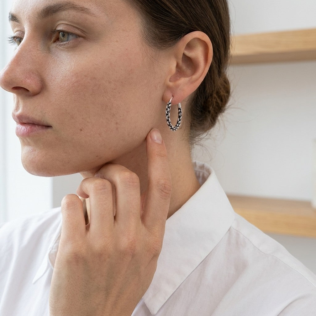 Aramat Jewels 16mm silver Bali hoop earrings with an ethnic braided design, worn by a woman.