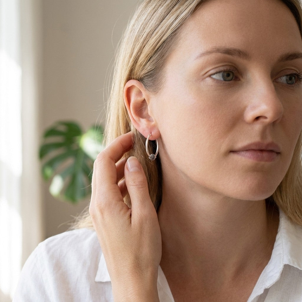 Aramat Jewels 18mm oval silver hoop earrings with intricate ethnic Bali design, worn by a woman.