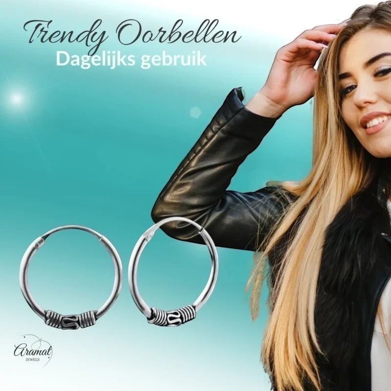 Aramat Jewels unisex silver Bali hoop earrings, 16mm diameter, with tribal-inspired detailing. A model with blonde hair and a leather jacket is partially visible.