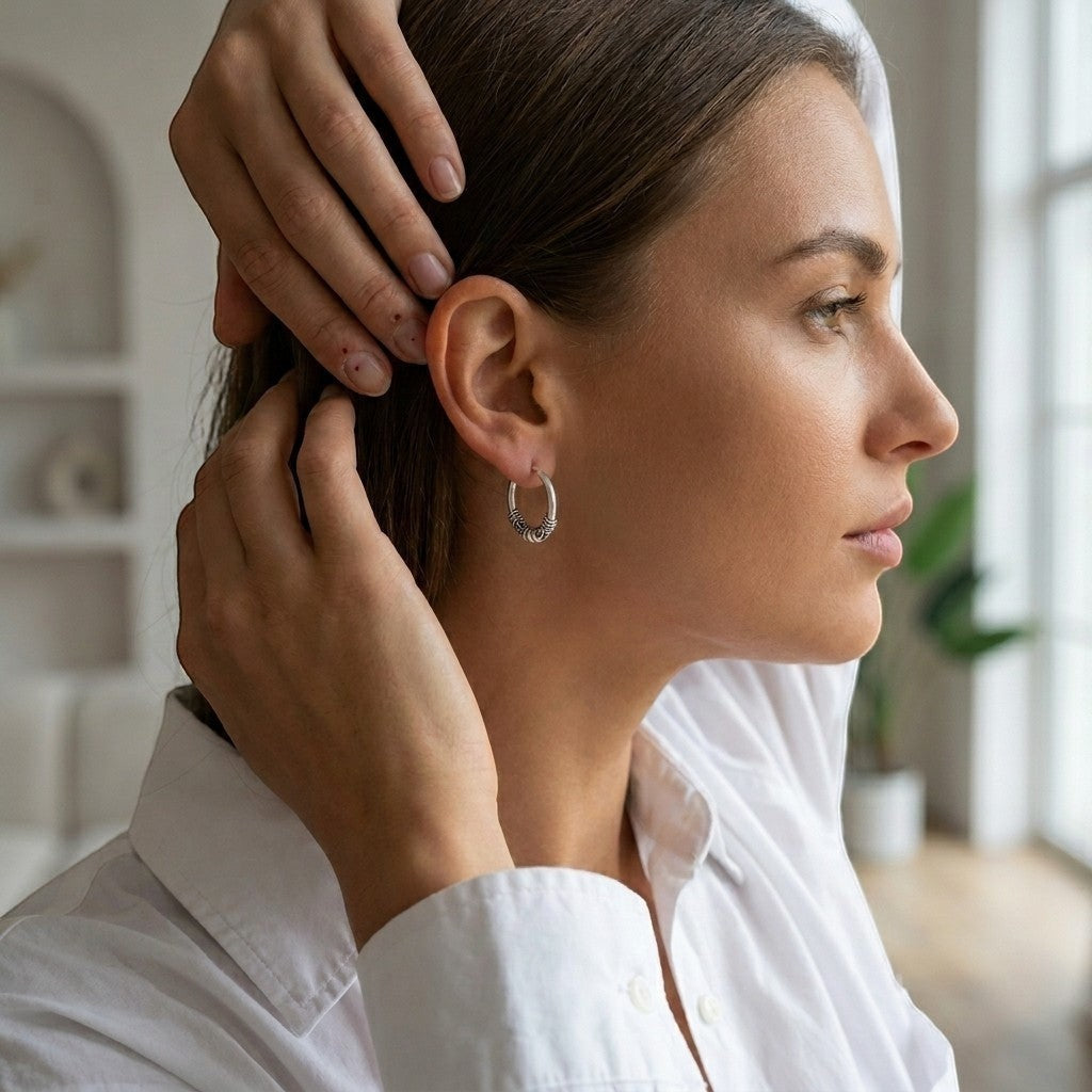 Aramat Jewels unisex 16mm silver Bali hoop earrings with intricate detailing, worn by a woman.