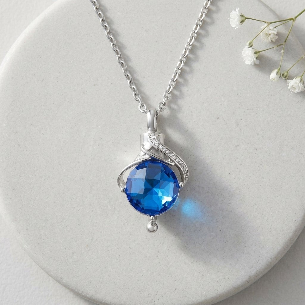 Aramat Jewels silver-tone stainless steel teardrop urn pendant with blue cubic zirconia and small accent stones.