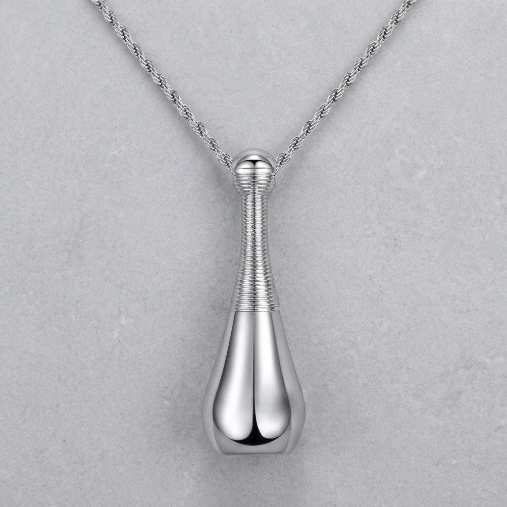 Aramat Jewels silver-colored 316L steel cone-shaped cremation pendant with a rope chain. The pendant has a ribbed texture on the neck and a smooth, teardrop-shaped base.