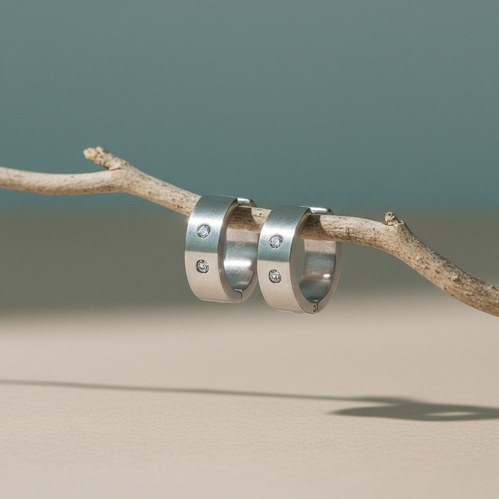 Aramat Jewels wide silver-tone huggie hoop earrings, 13x7mm, with two clear crystals and a hinge closure.
