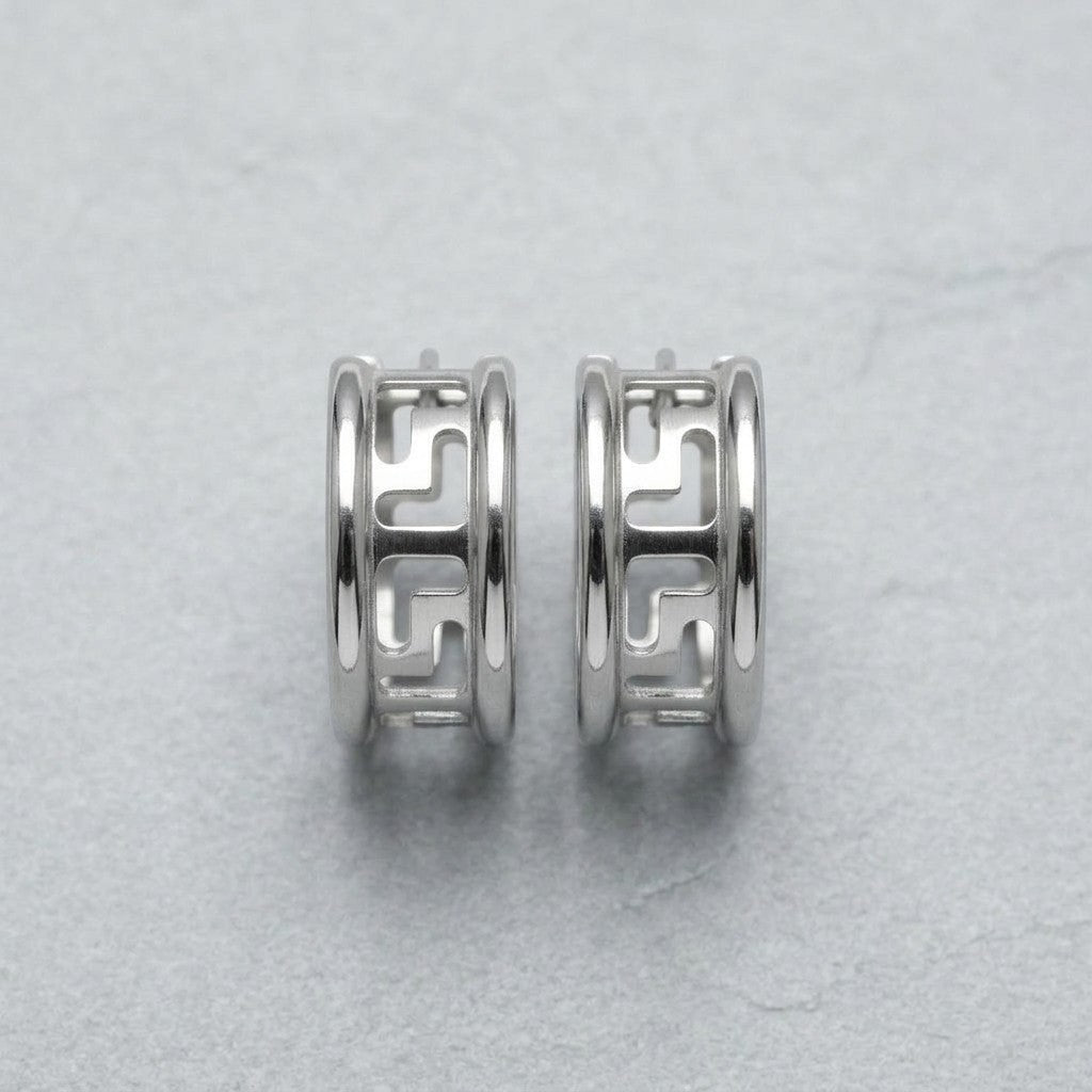 Aramat Jewels silver-tone stainless steel hoop earrings with a cut-out Greek key pattern, 20mm diameter.