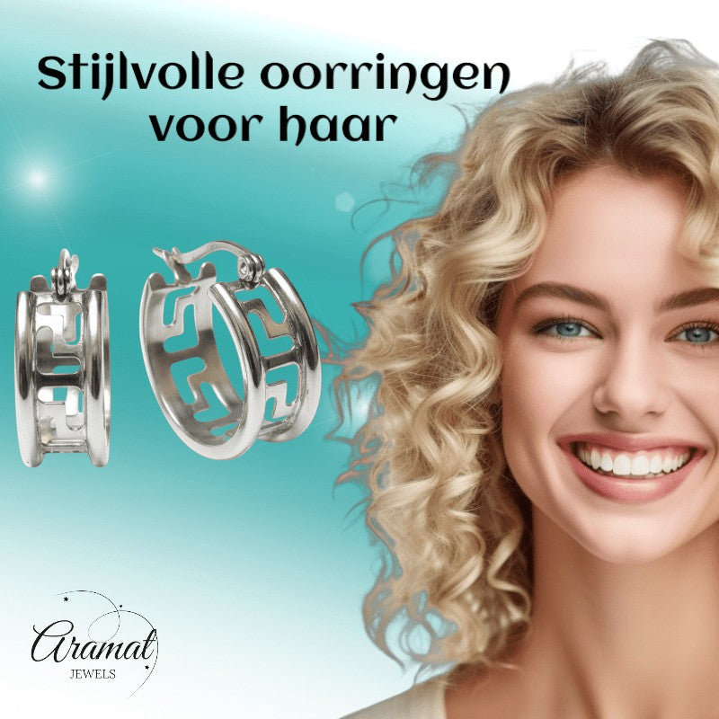 Aramat Jewels silver-tone stainless steel hoop earrings with Greek motif, 20mm diameter, worn by a smiling blonde model.