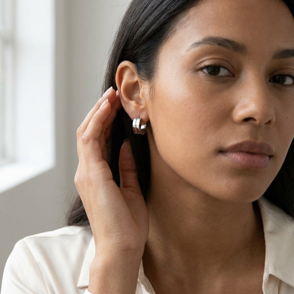 Aramat Jewels silver-tone stainless steel huggie hoop earrings with a subtle accent detail.