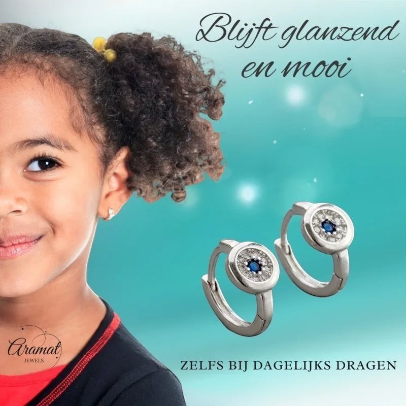 Aramat Jewels silver hoop earrings with blue and clear cubic zirconia, 12mm, worn by a smiling young girl.