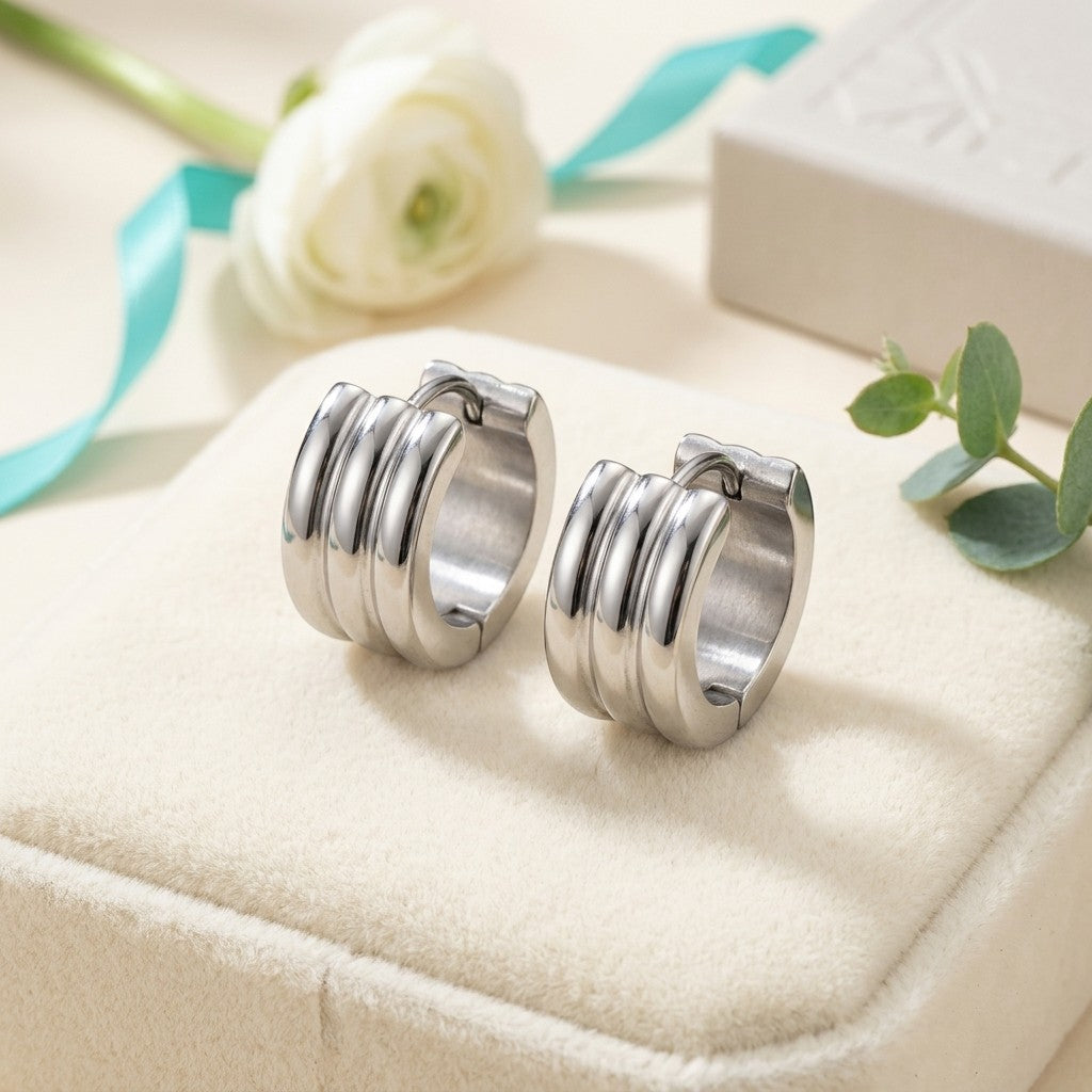 Aramat Jewels wide silver-tone stainless steel hoop earrings with ribbed detail.