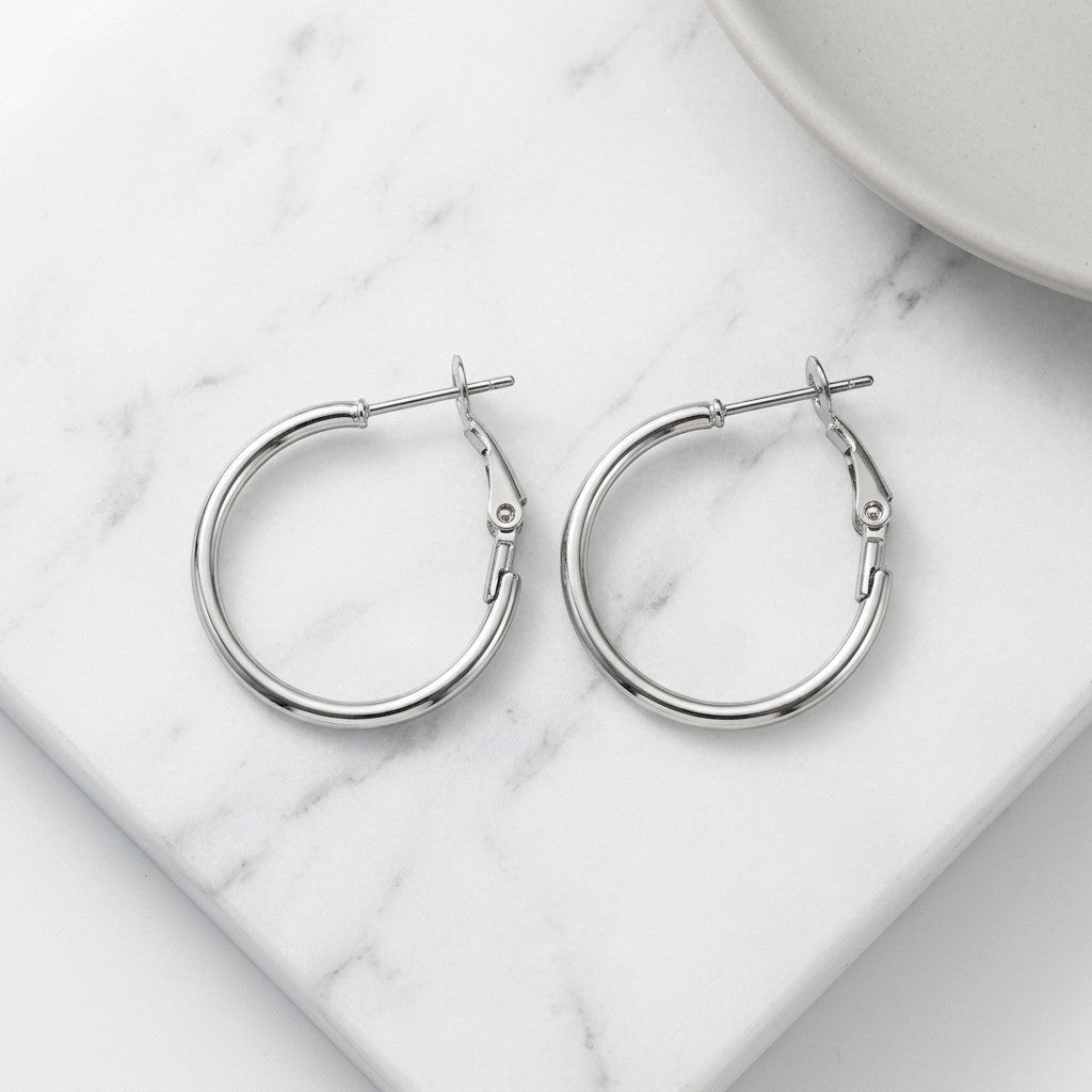 Aramat Jewels silver stainless steel hoop earrings with a high-gloss finish and hinge closure, available in multiple sizes.