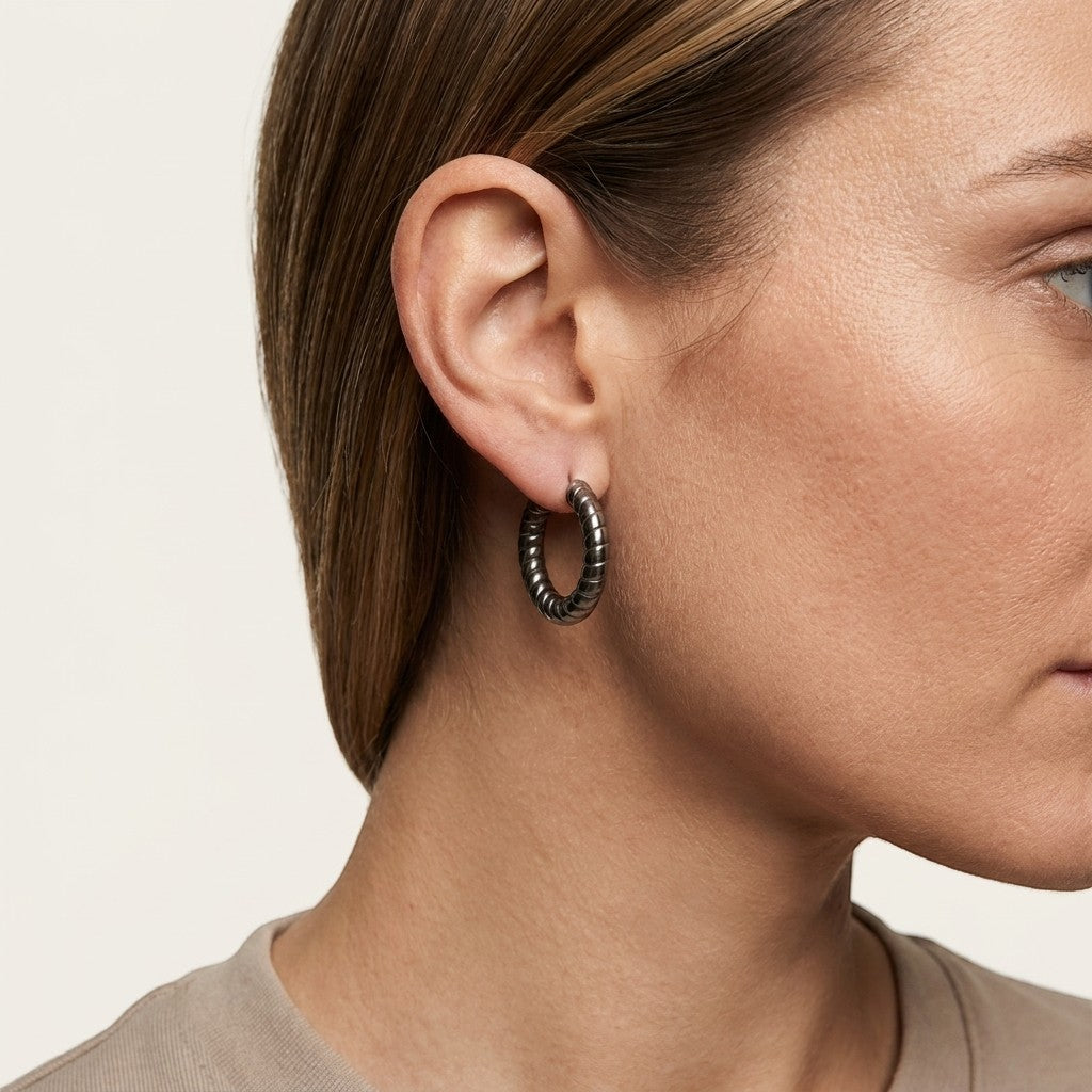 Aramat Jewels silver-coloured hollow steel hoop earrings with a ribbed stripe motif, 30mm diameter.