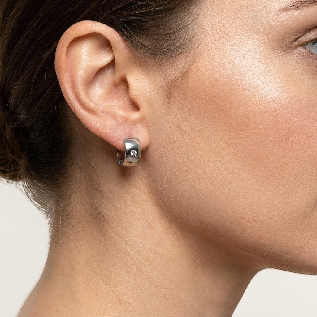 Aramat Jewels silver-coloured wide stainless steel hoop earrings with a single clear zirconia stone.