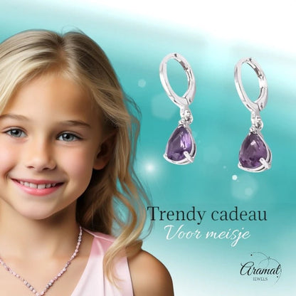 Aramat Jewels silver huggie earrings with dangling purple teardrop zirconia stones, worn by a smiling young girl.