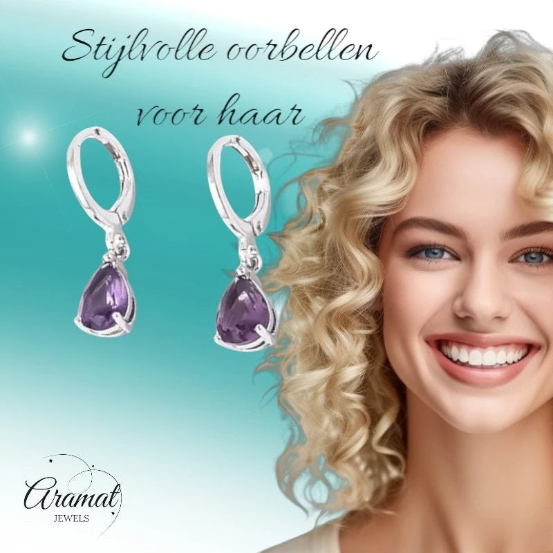 Aramat Jewels silver stainless steel huggie earrings with a dangling purple teardrop zirconia stone on a smiling model