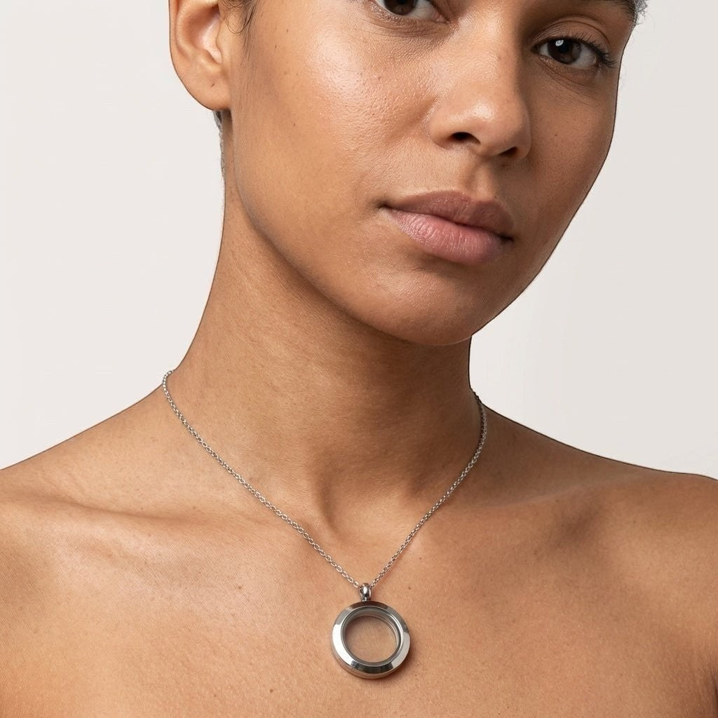 Aramat Jewels silver-colored 15mm round stainless steel locket necklace on a model. Subtle memorial jewelry with screw closure.