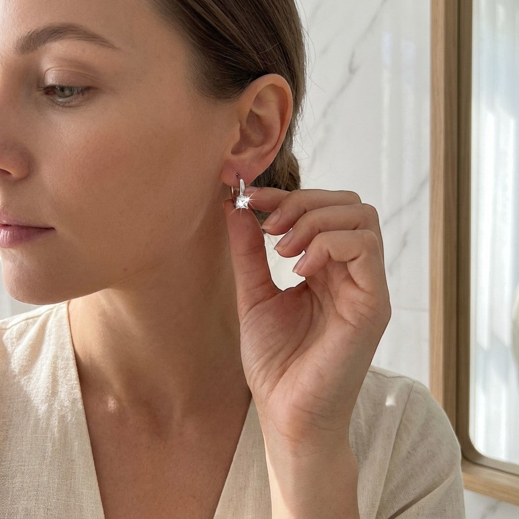 Aramat Jewels silver-tone hoop earrings with a square clear cubic zirconia stone, worn by a woman.
