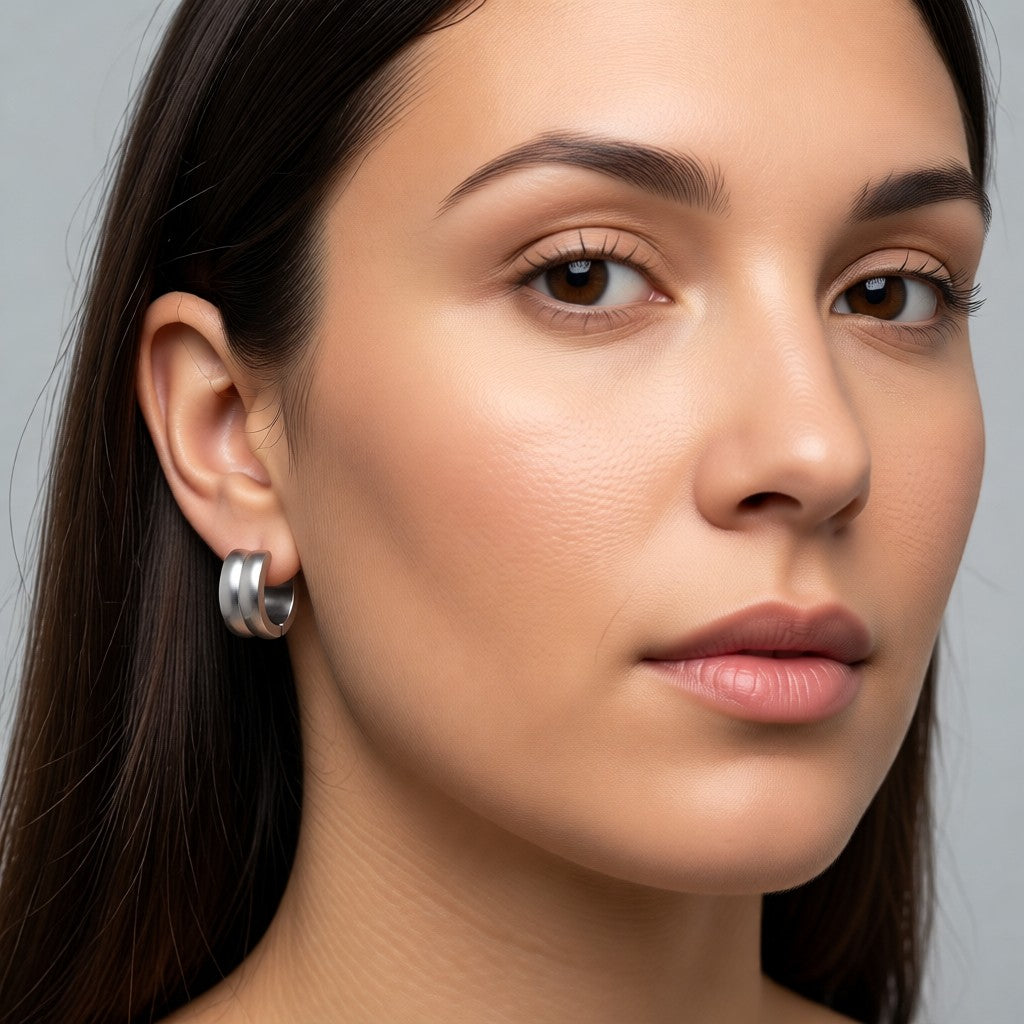 Aramat Jewels silver-tone stainless steel huggie hoop earrings with double stripe detail, 13mm diameter.