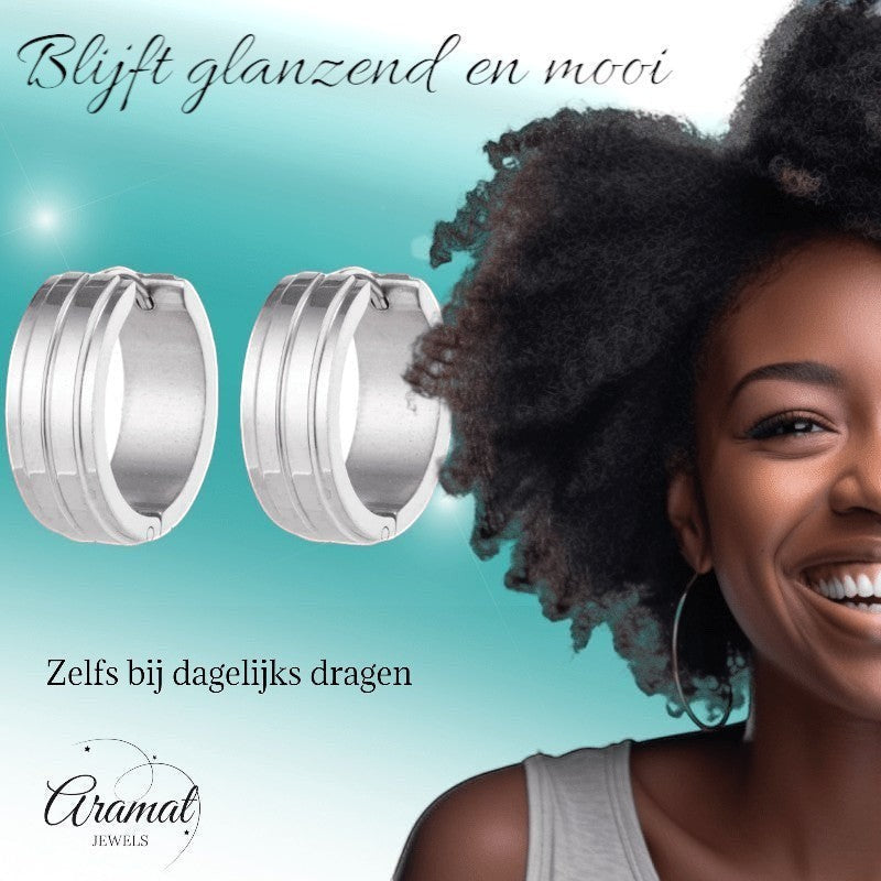 Aramat Jewels silver-tone stainless steel hoop earrings with double stripe detail, 20mm diameter, worn by a smiling Black woman with natural hair.