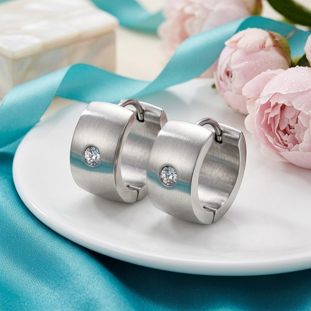 Aramat Jewels wide silver-tone stainless steel hoop earrings with a single clear cubic zirconia stone.