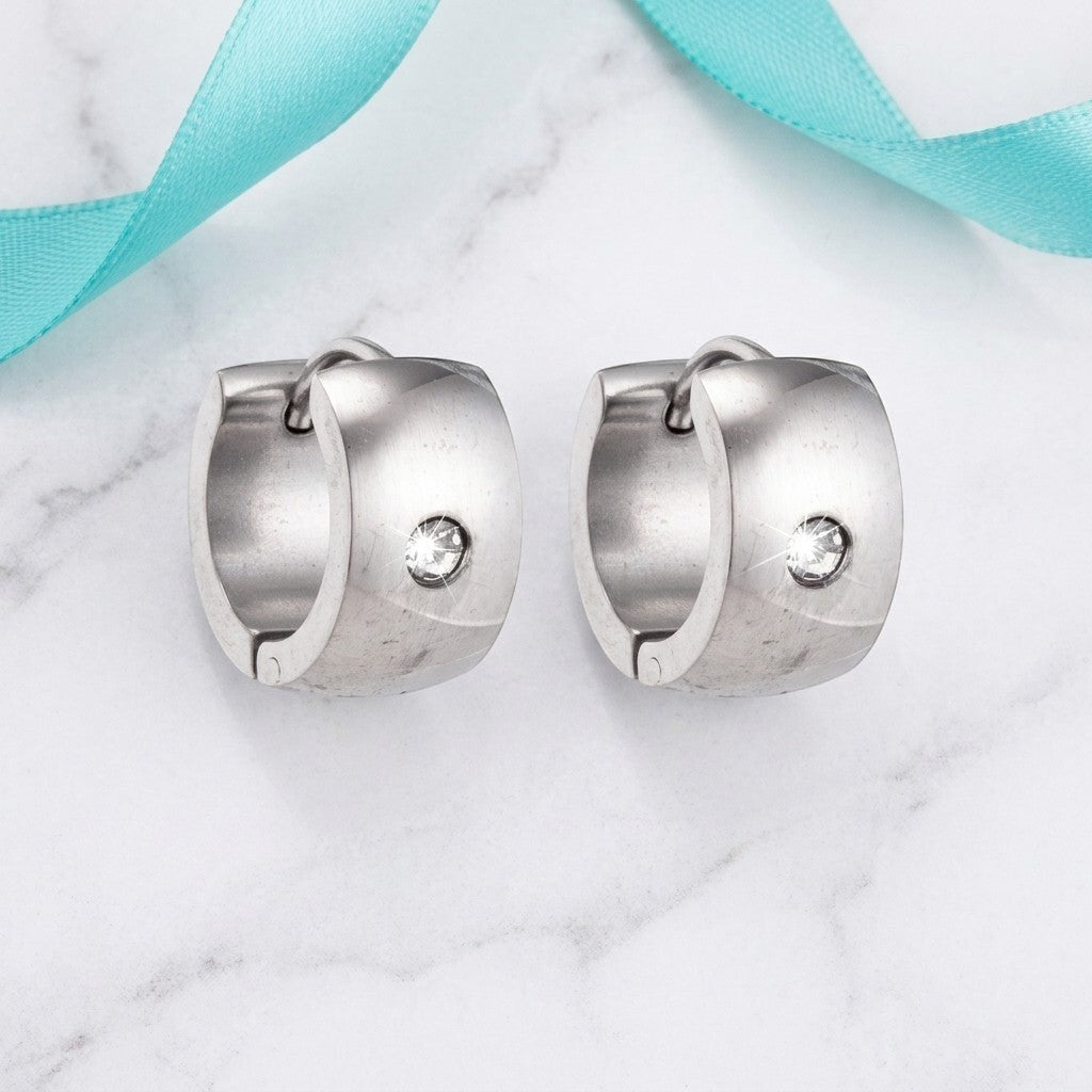 Aramat Jewels wide silver-tone stainless steel hoop earrings with a single clear cubic zirconia stone.