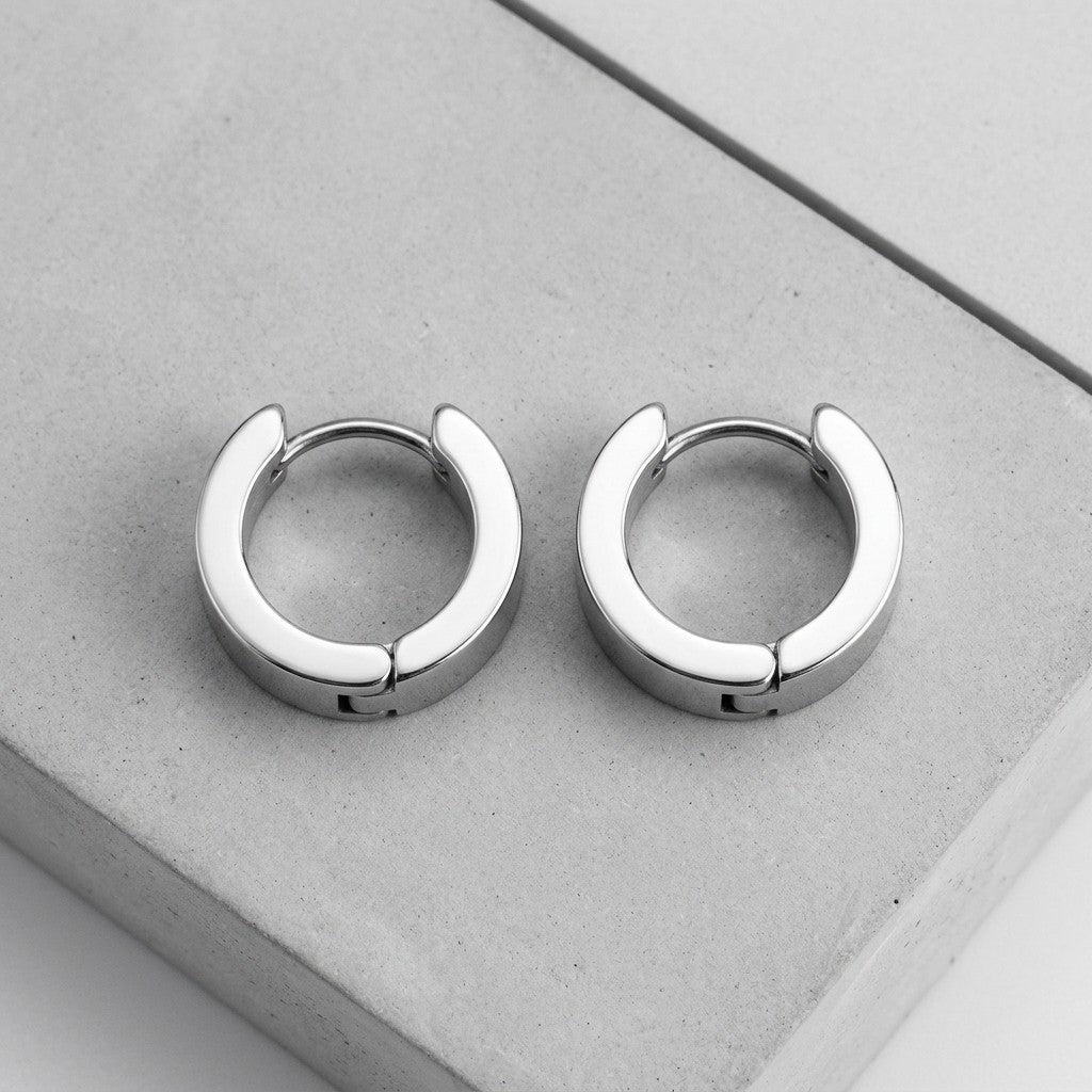 Aramat Jewels silver-colored stainless steel huggie hoop earrings, 13mm diameter, 7mm wide, smooth finish.