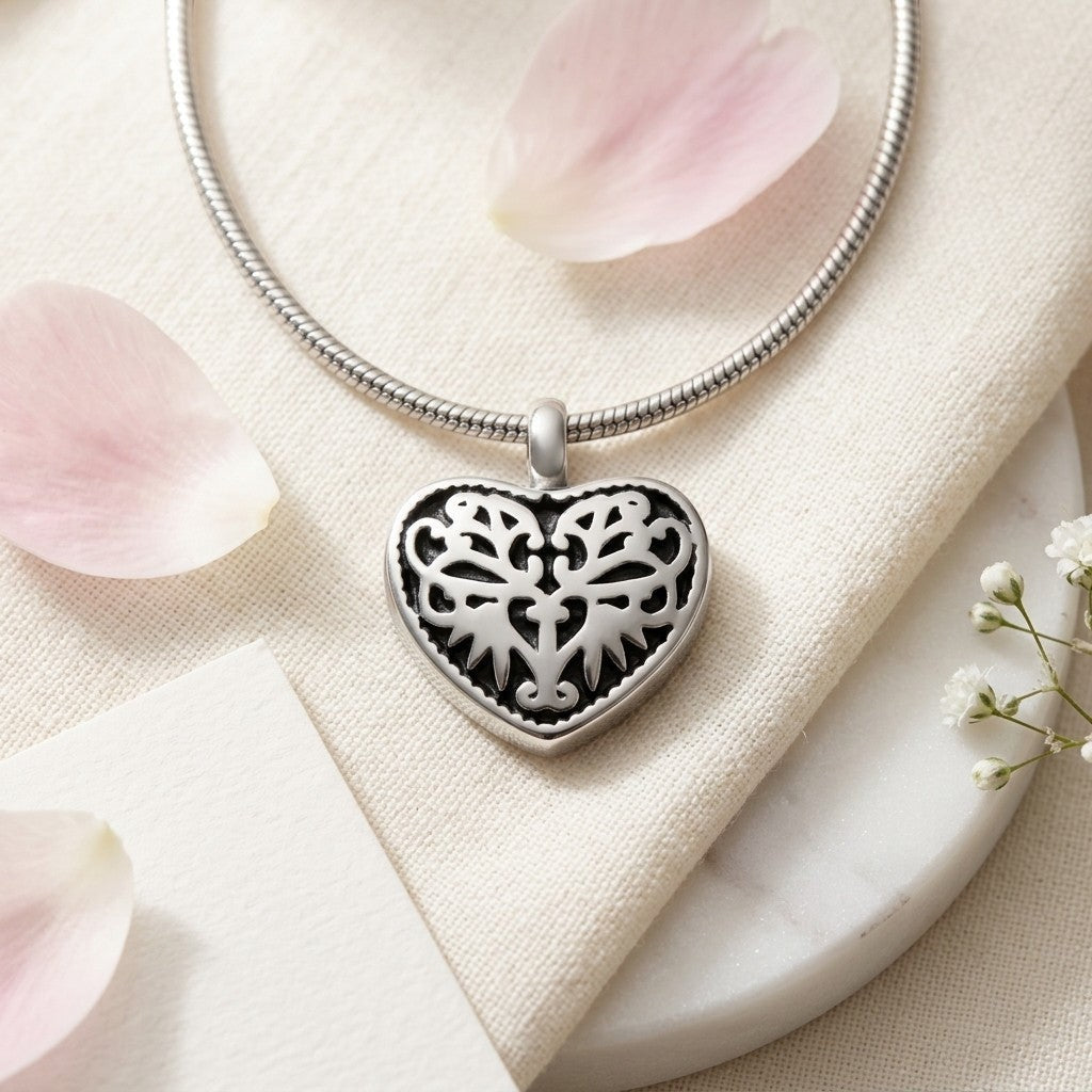 Aramat Jewels silver-coloured steel heart-shaped cremation pendant with black enamel inlay and intricate filigree design.