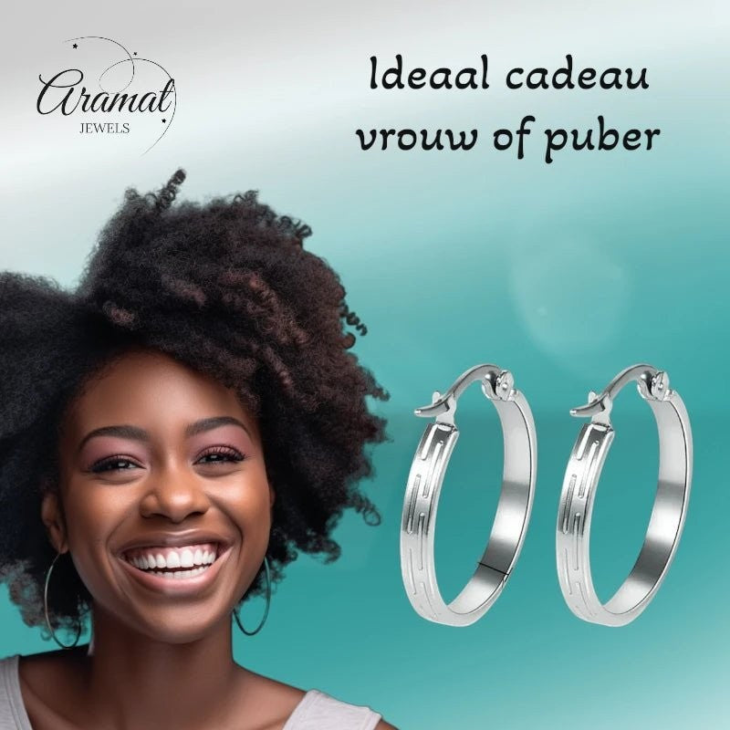 Aramat Jewels silver stainless steel hoop earrings with striped motif, 20mm diameter, worn by a smiling Black woman.