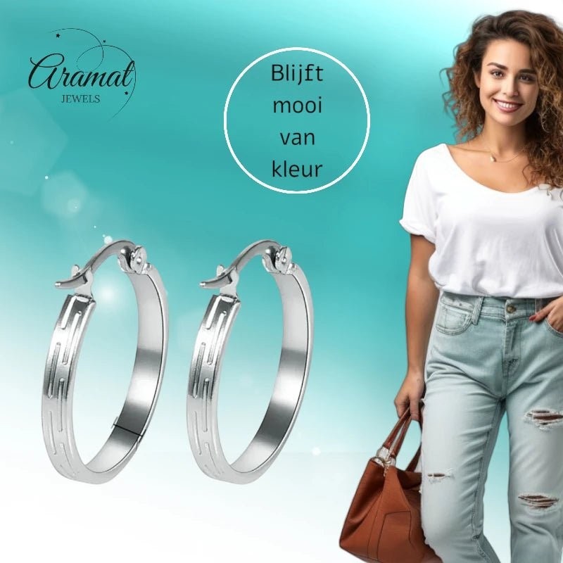 Aramat Jewels silver stainless steel hoop earrings with striped motif, 20mm diameter, worn by a smiling woman in ripped jeans.