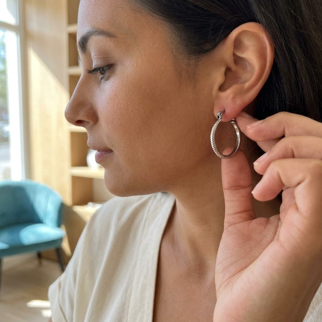 Aramat Jewels silver-tone stainless steel hoop earrings with a striped texture, 18mm diameter, worn by a woman.