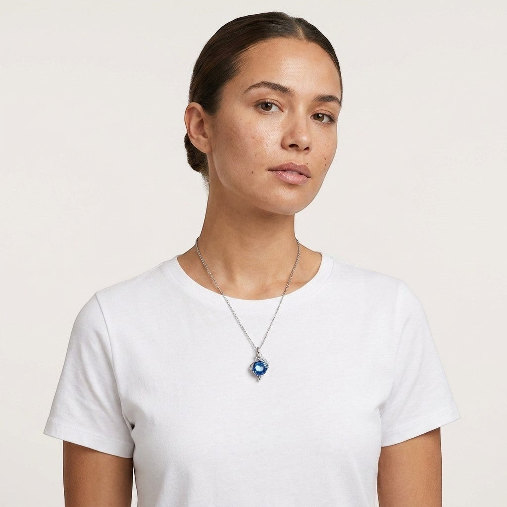 Aramat Jewels silver-tone stainless steel teardrop ash pendant with blue zirconia, 31x18mm, worn by a woman.