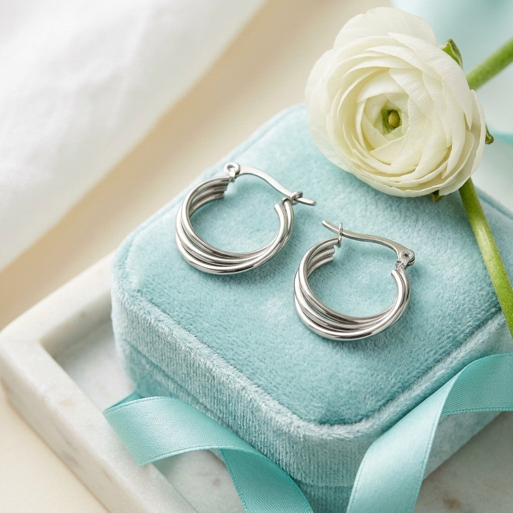 Aramat Jewels silver-tone stainless steel triple hoop earrings, 16mm diameter, with a hinge clasp, presented on a teal velvet box.