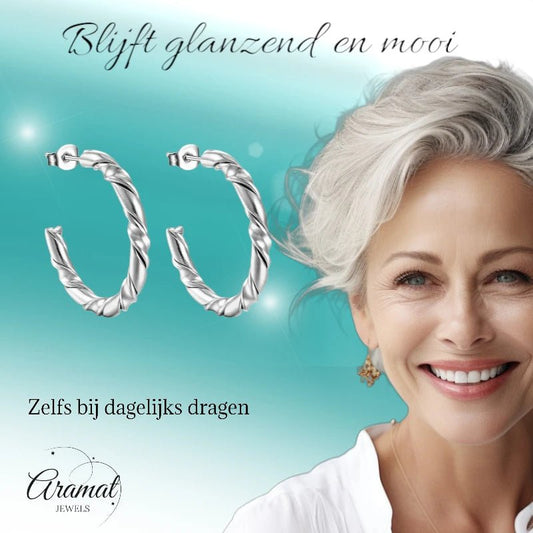 Aramat Jewels silver-colored stainless steel hoop earrings with a twisted rope pattern, worn by a smiling woman.
