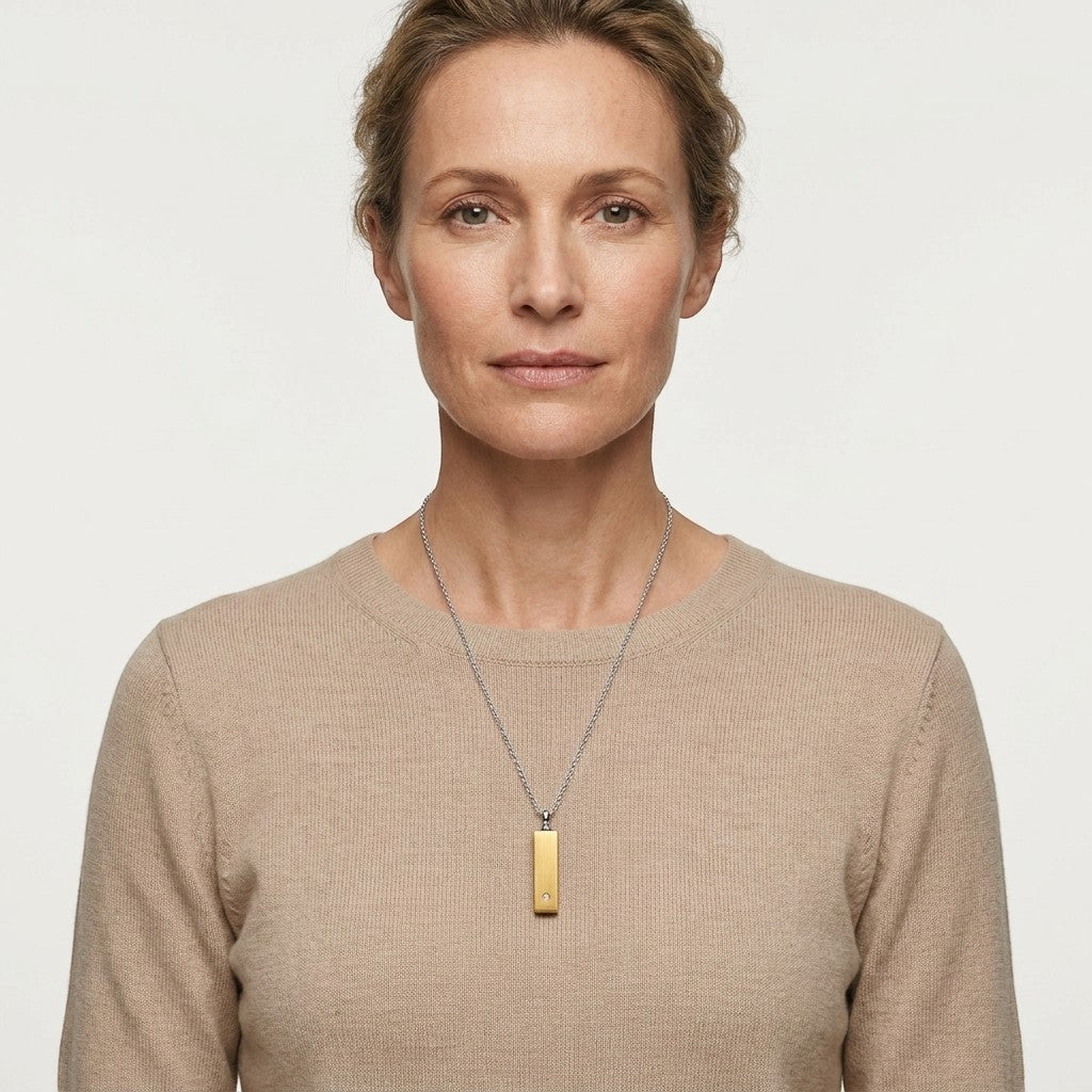 Aramat Jewels staaf ashanger van 4cm in goudkleurig roestvrij staal met een zirkonia, gedragen door een model.