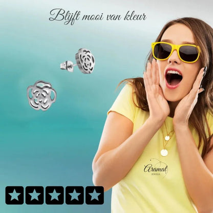 Aramat Jewels stainless steel open rose stud earrings in silver, worn by a woman in a yellow shirt and sunglasses.