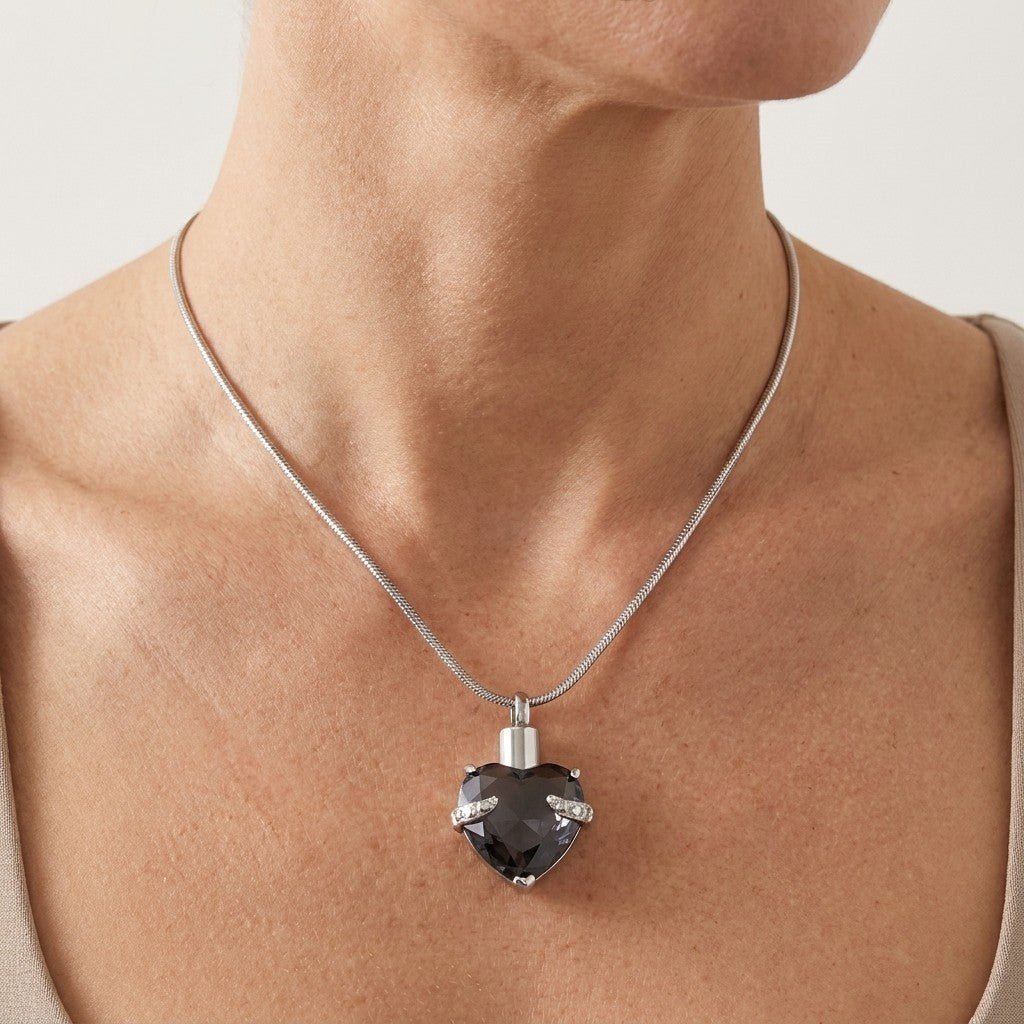 Aramat Jewels stalen ashanger hartvormig met grote grijze steen en zirkonia accenten, gedragen aan een zilverkleurige slangenhalsketting.