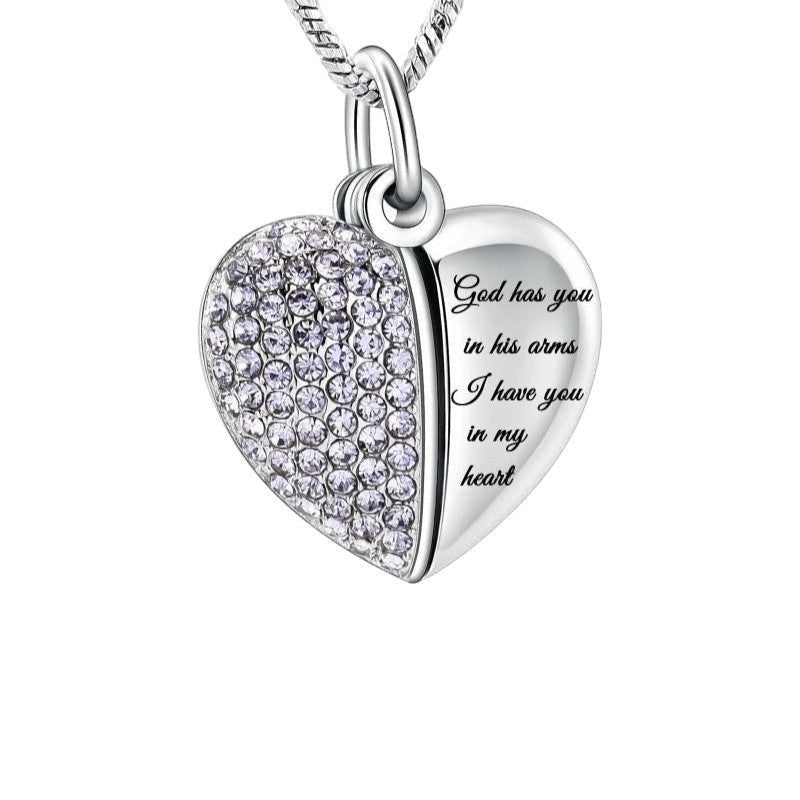 Aramat Jewels stalen hartvormige ashanger met lila kristallen en de tekst "God has you in his arms, I have you in my heart".