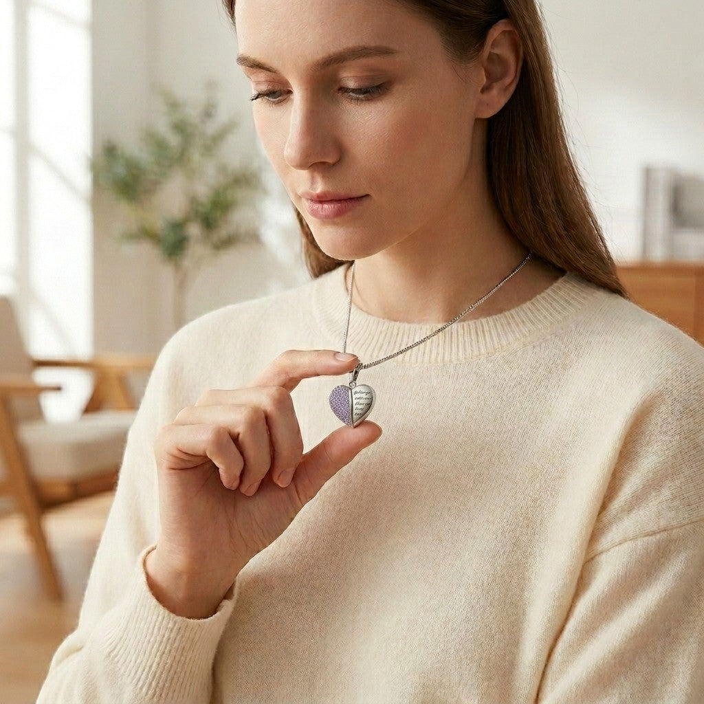 Aramat Jewels stalen hartvormige ashanger met lila kristal en gravure 'God has you in his arms, I have you in my heart'.