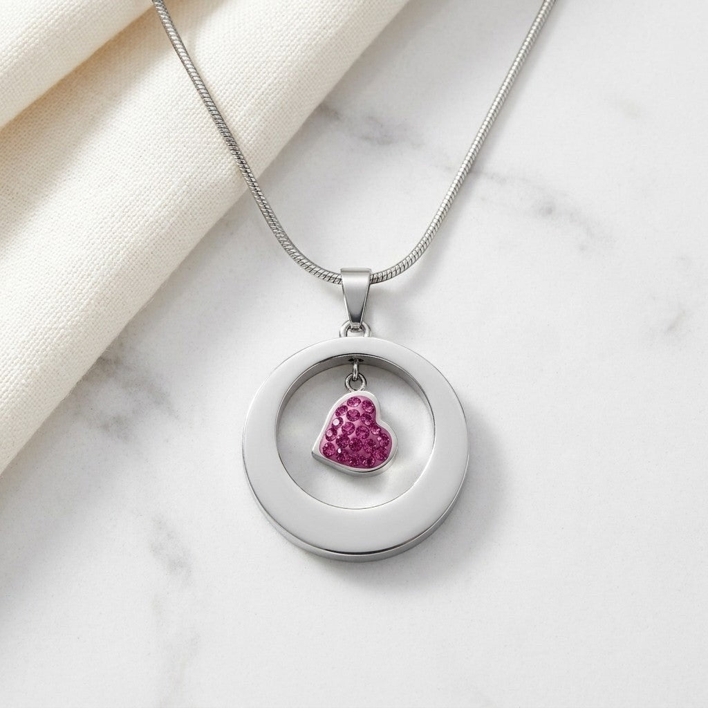 Aramat Jewels® zilverkleurige stalen ashanger rond met een hartje bezet met roze steentjes.