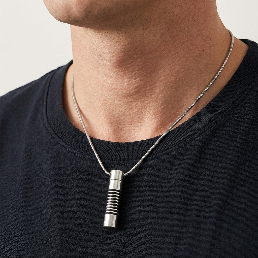 Aramat Jewels zilverkleurige stalen buis ashanger voor mannen met zwarte ringen, gedragen aan een slangenketting.