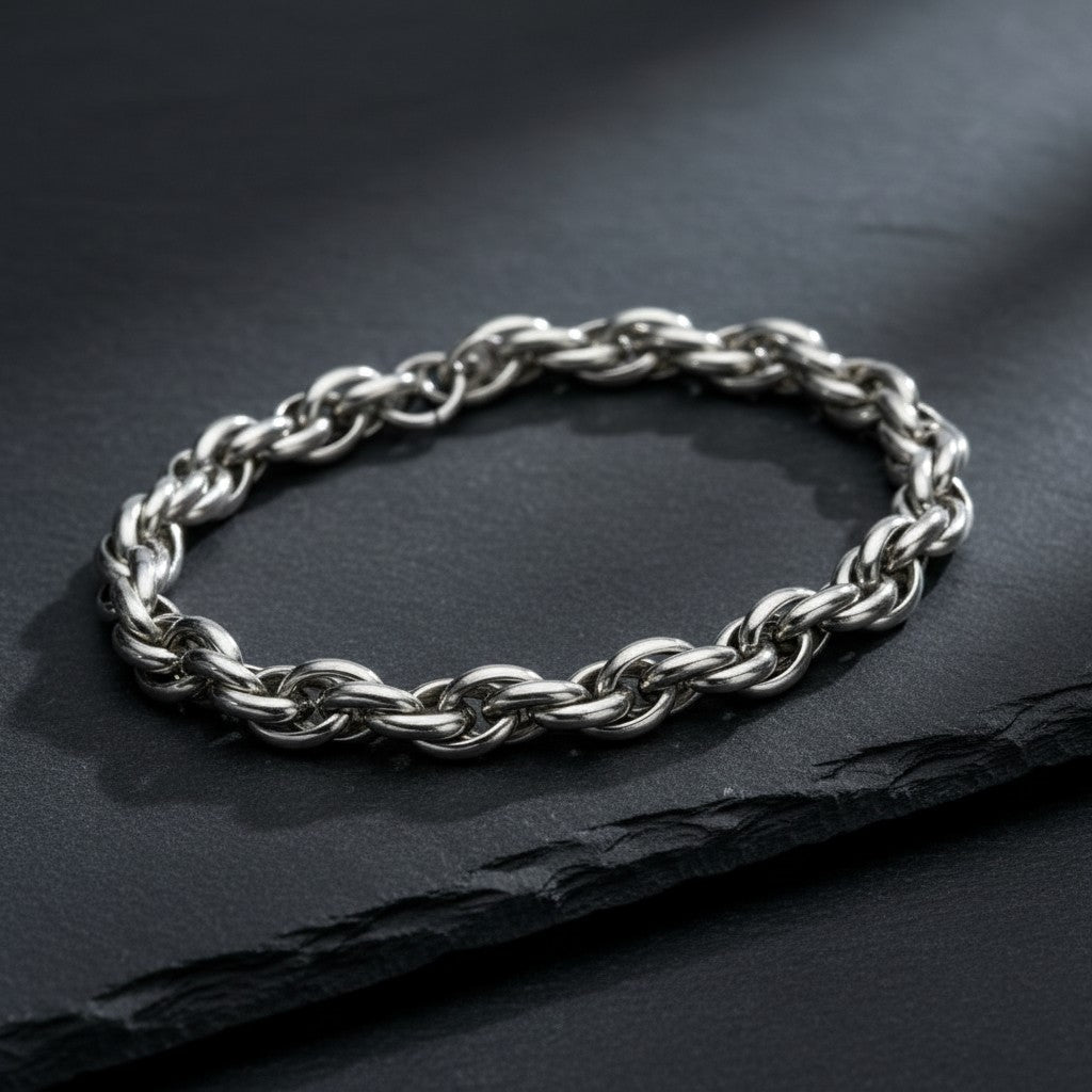 Zilverkleurige Aramat Jewels gevlochten armband van RVS, 7 mm breed en 22 cm lang, gepresenteerd op een zwarte ondergrond