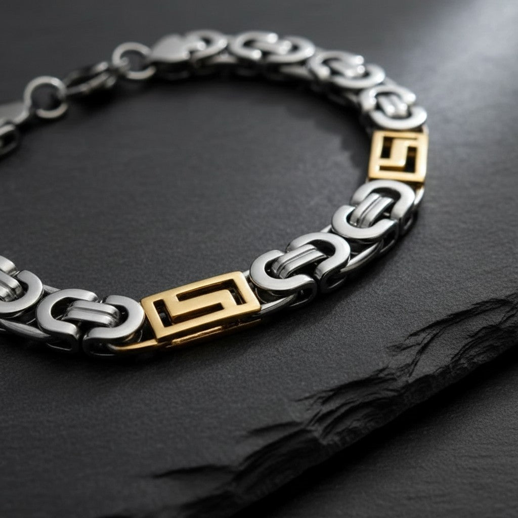 Aramat Jewels bicolor koningsarmband van 316L roestvrij staal met zilveren en gouden details op een zwarte ondergrond.