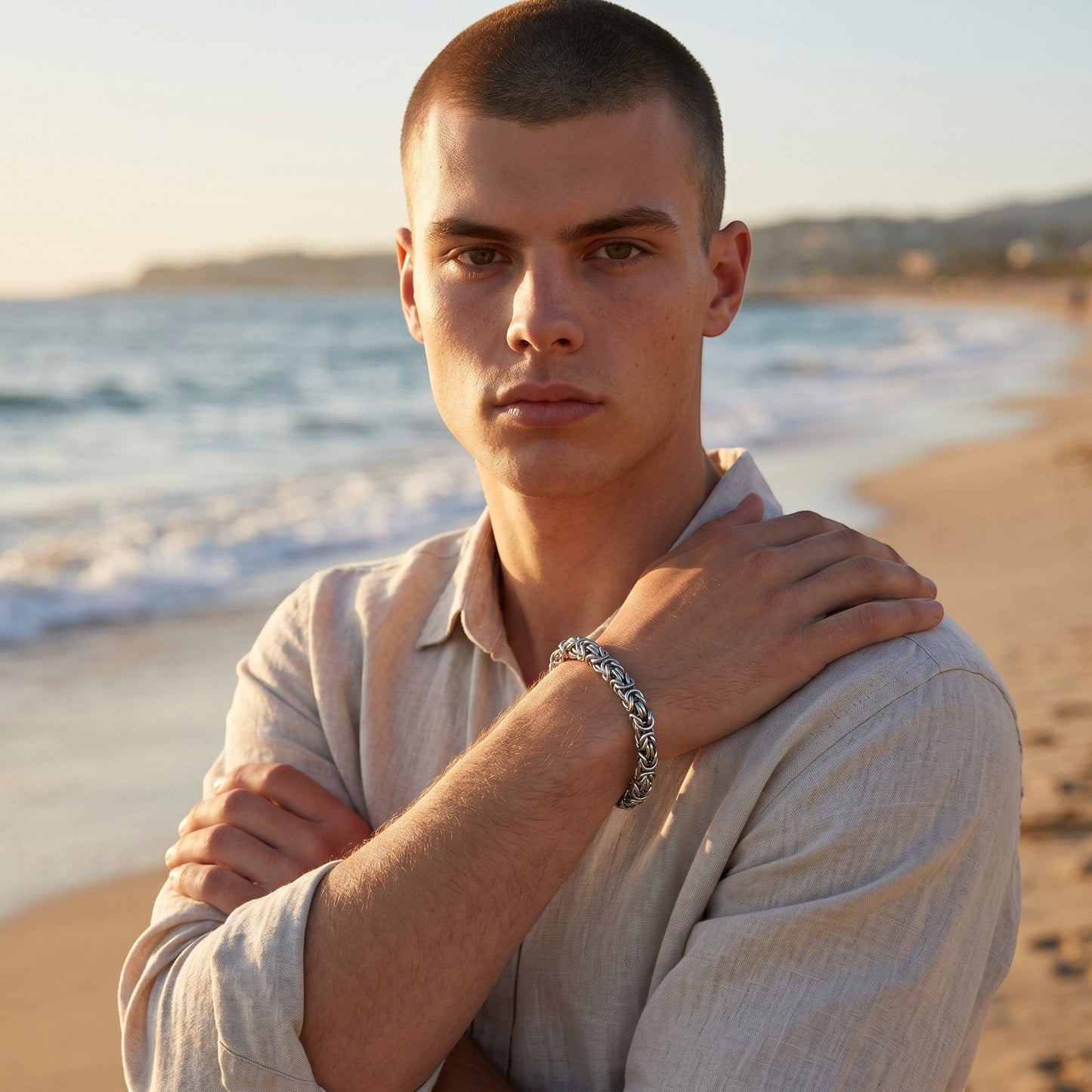 Aramat Jewels stalen koningsarmband met byzantijnse schakel, zilverkleurig, 7mm breed, gedragen door een man op het strand.