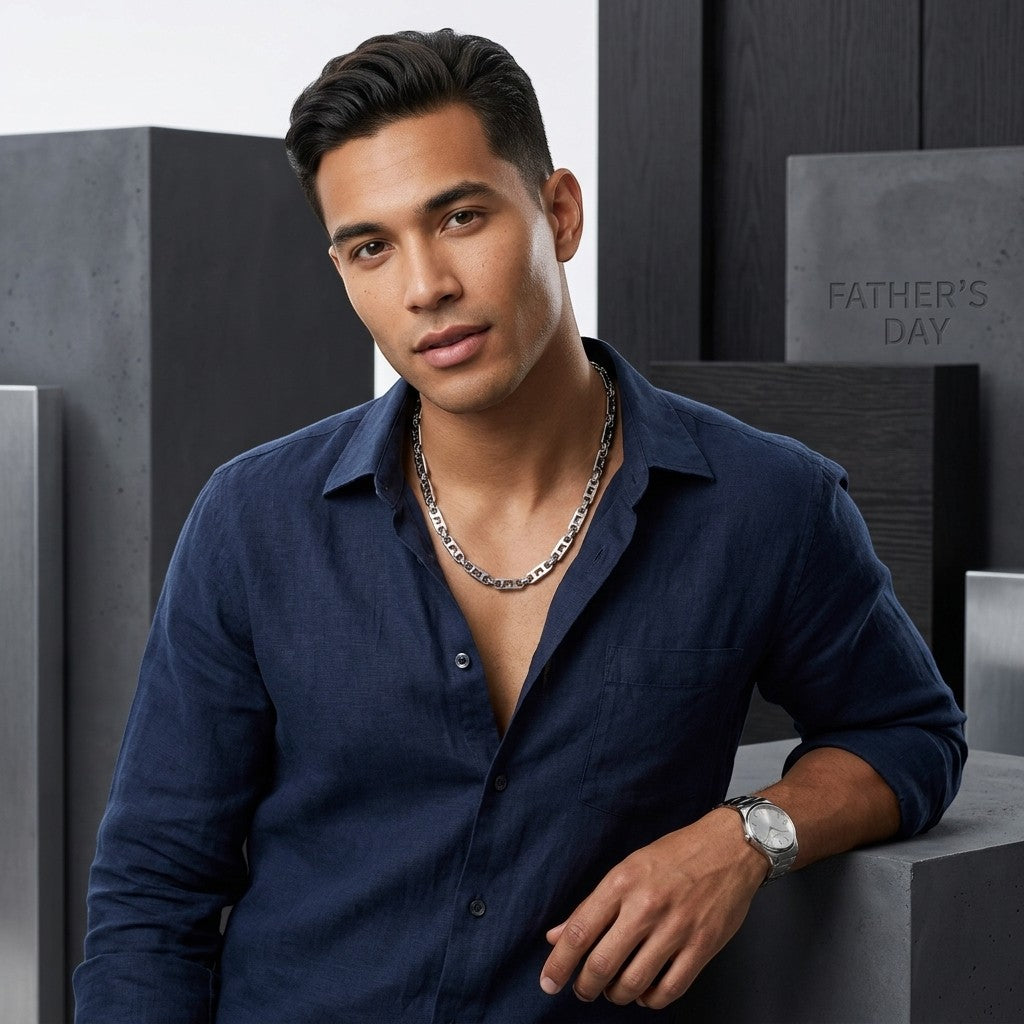 Man draagt een brede Aramat Jewels stalen koningsketting met kroonmotief en marine schakels bij een donkerblauw overhemd.