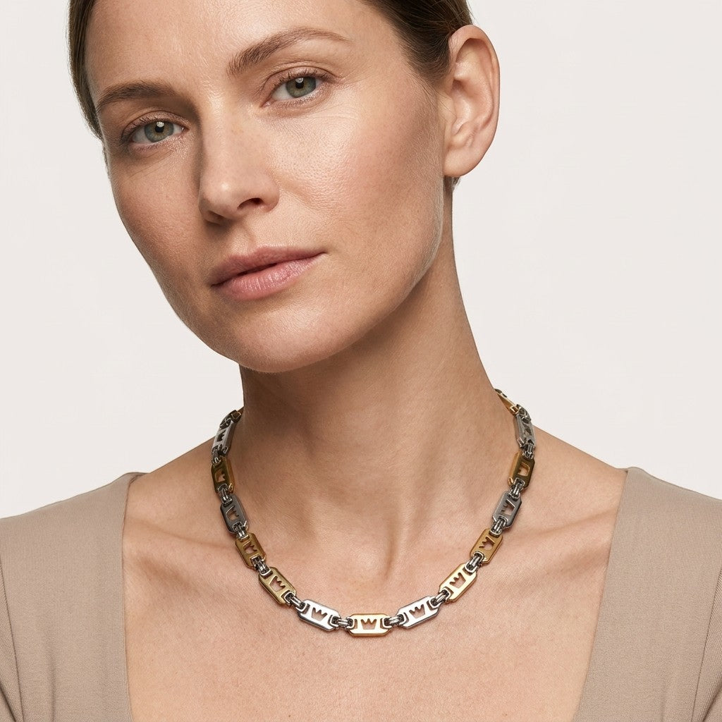 Aramat Jewels brede stalen koningsketting met kroonmotief en tweekleurige schakels gedragen door een vrouw.