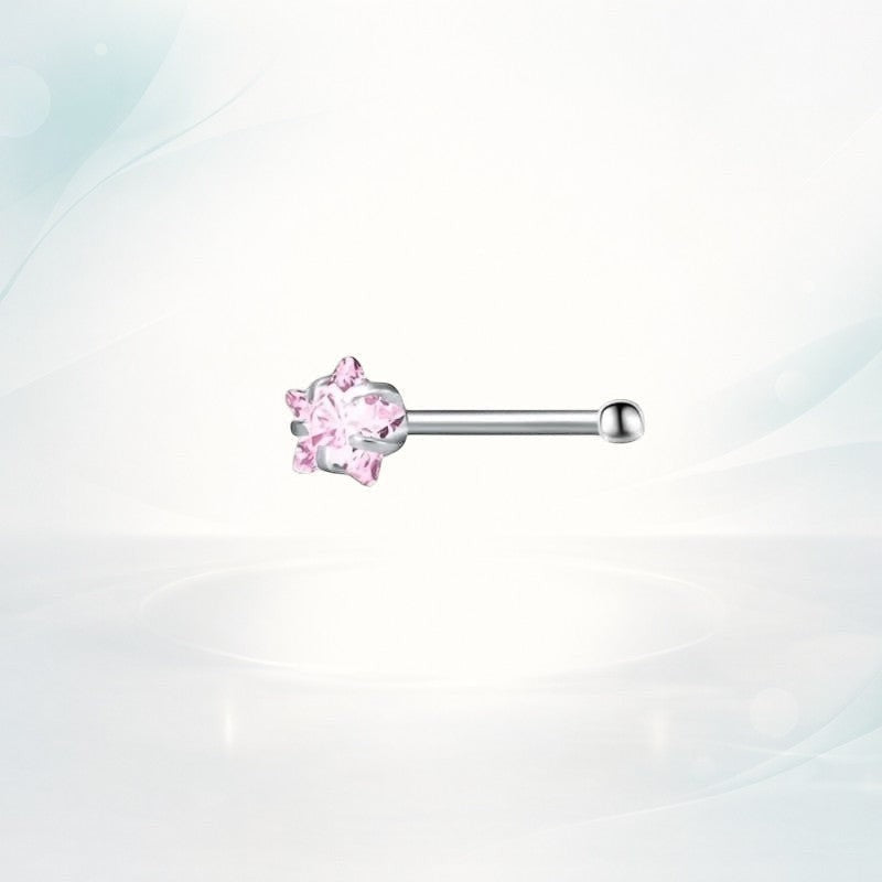 Aramat Jewels stalen neuspiercing met een roze zirkonia steen in stervorm op een lichtgekleurde achtergrond.